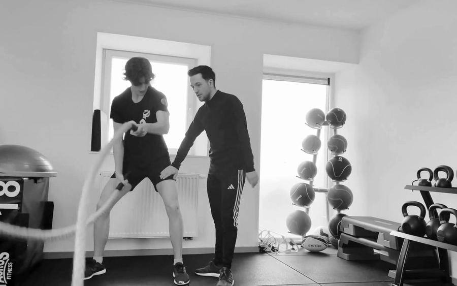 Jeune footballeur en rééducation active aux cordes ondulatoires, corrigé par son kinésithérapeute